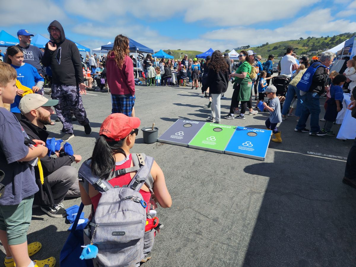 Children and mom playing a waste sorting cornhole game.